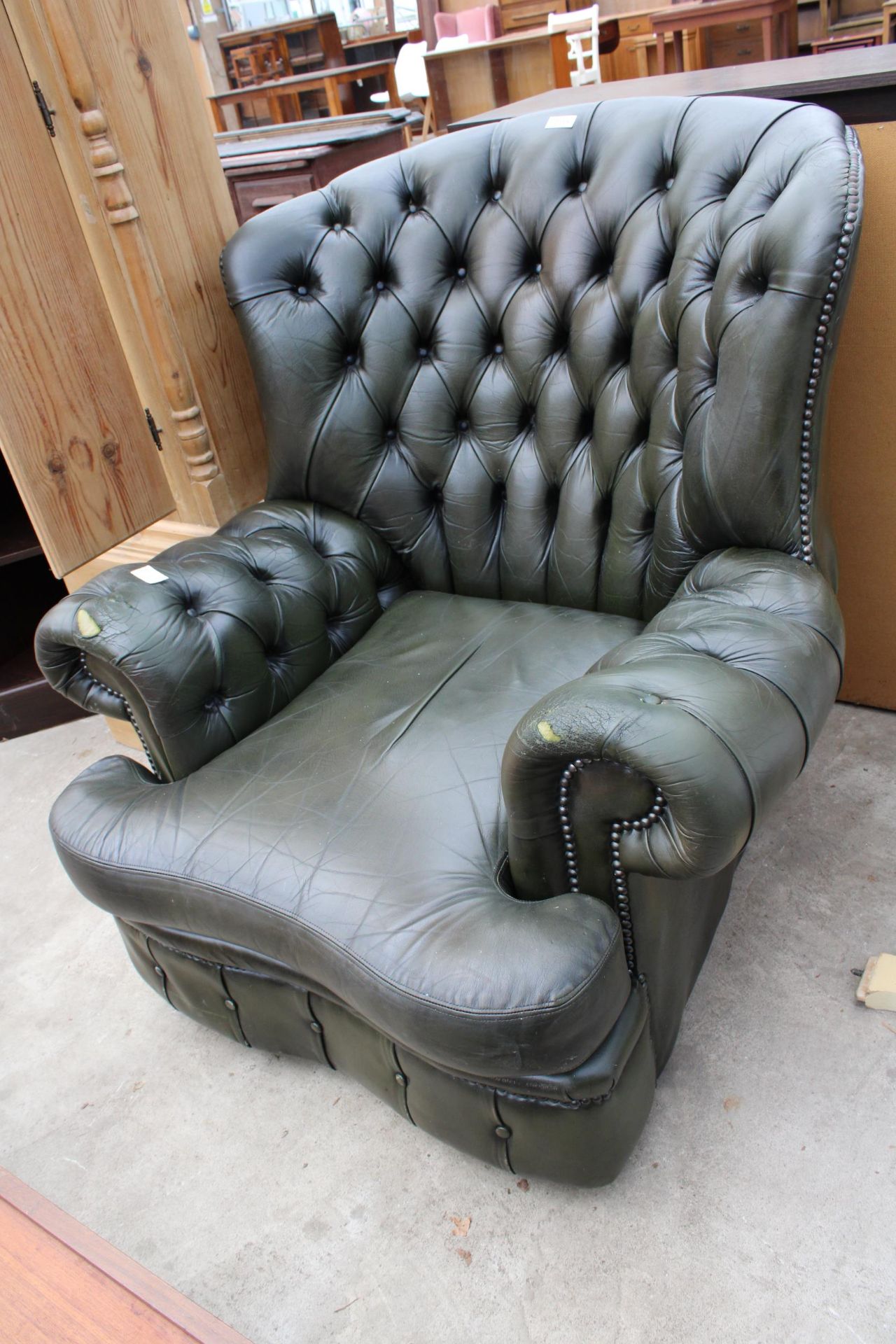 A MODERN GREEN LEATHER BUTTON-BACK WINGED EASY CHAIR