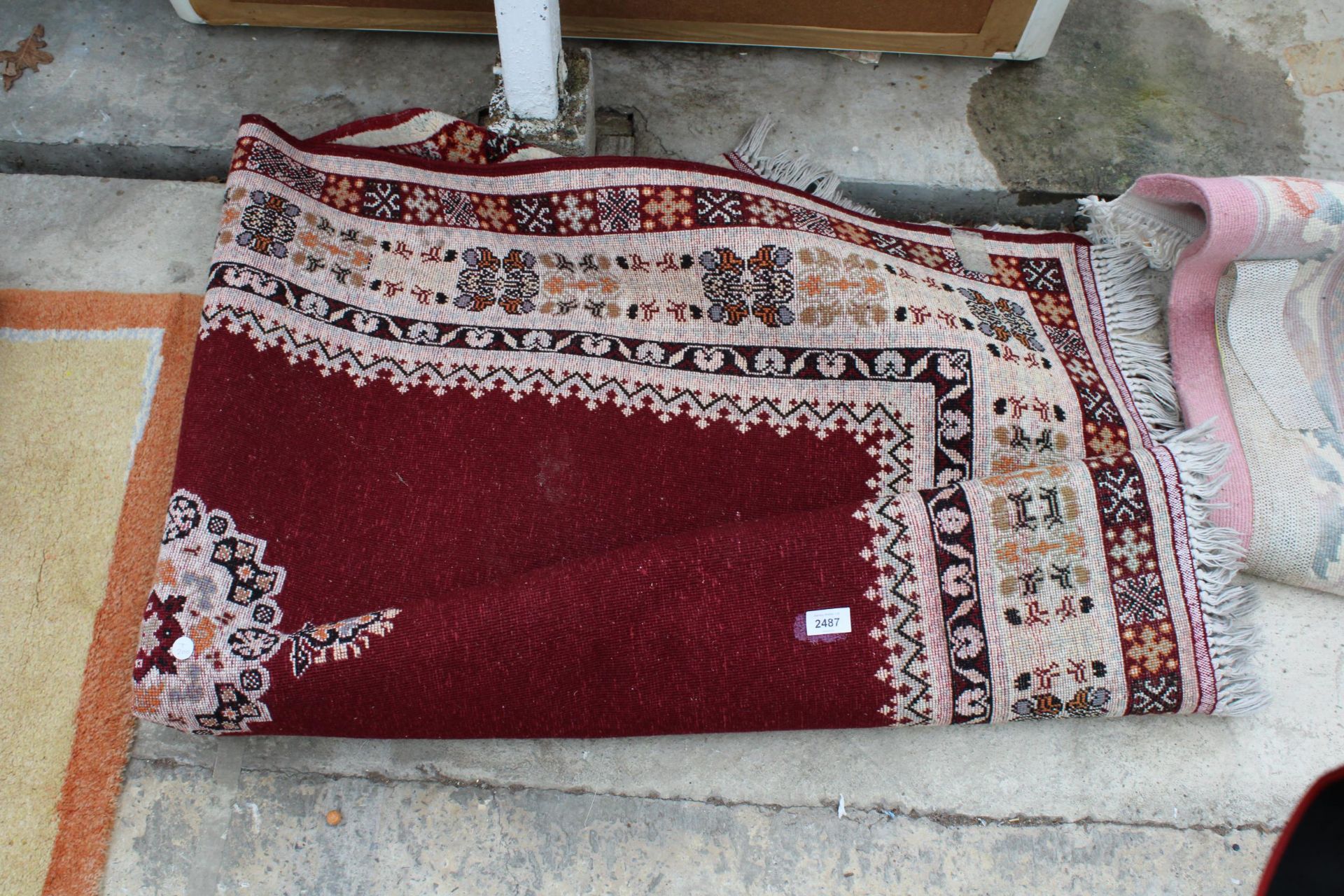 A VINTAGE RED PATTERNED FRINGED RUG