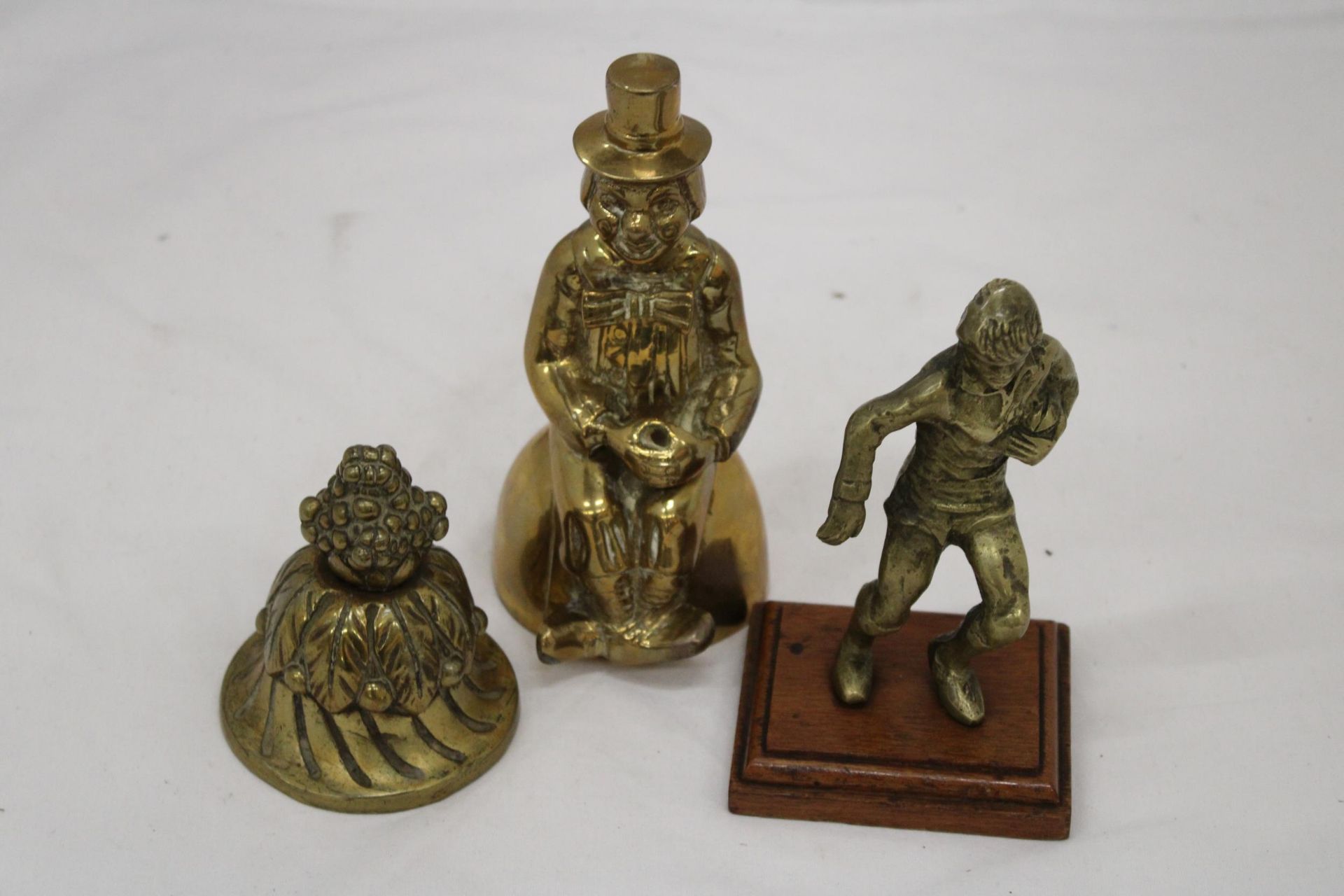 THREE BRASS ITEMS TO INCLUDE A HEAVY PAPERWEIGHT, CLOWN AND RUGBY PLAYER