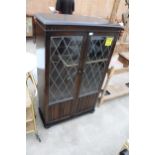 AN OAK TWO DOOR BOOKCASE WITH GLAZED, LEADED AND LINENFOLD DOORS, 31" WIDE