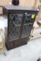 AN OAK TWO DOOR BOOKCASE WITH GLAZED, LEADED AND LINENFOLD DOORS, 31" WIDE