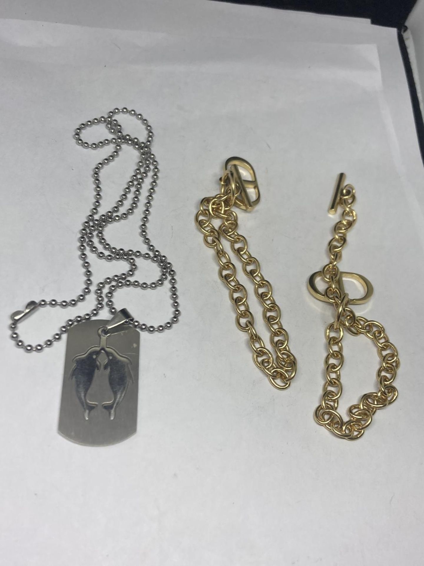 TWO GOLD PLATED T BAR BRACELETS AND A WHITE METAL DOLPHIN PENDANT NECKLACE