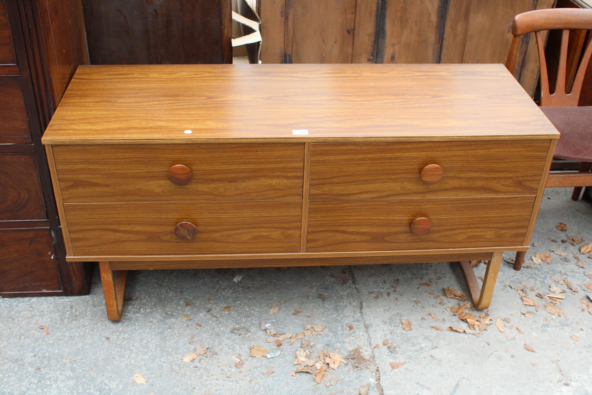 A RETRO TEAK EFFECT CHEST OF FOUR DRAWERS ON OPEN BASE 51" WIDE