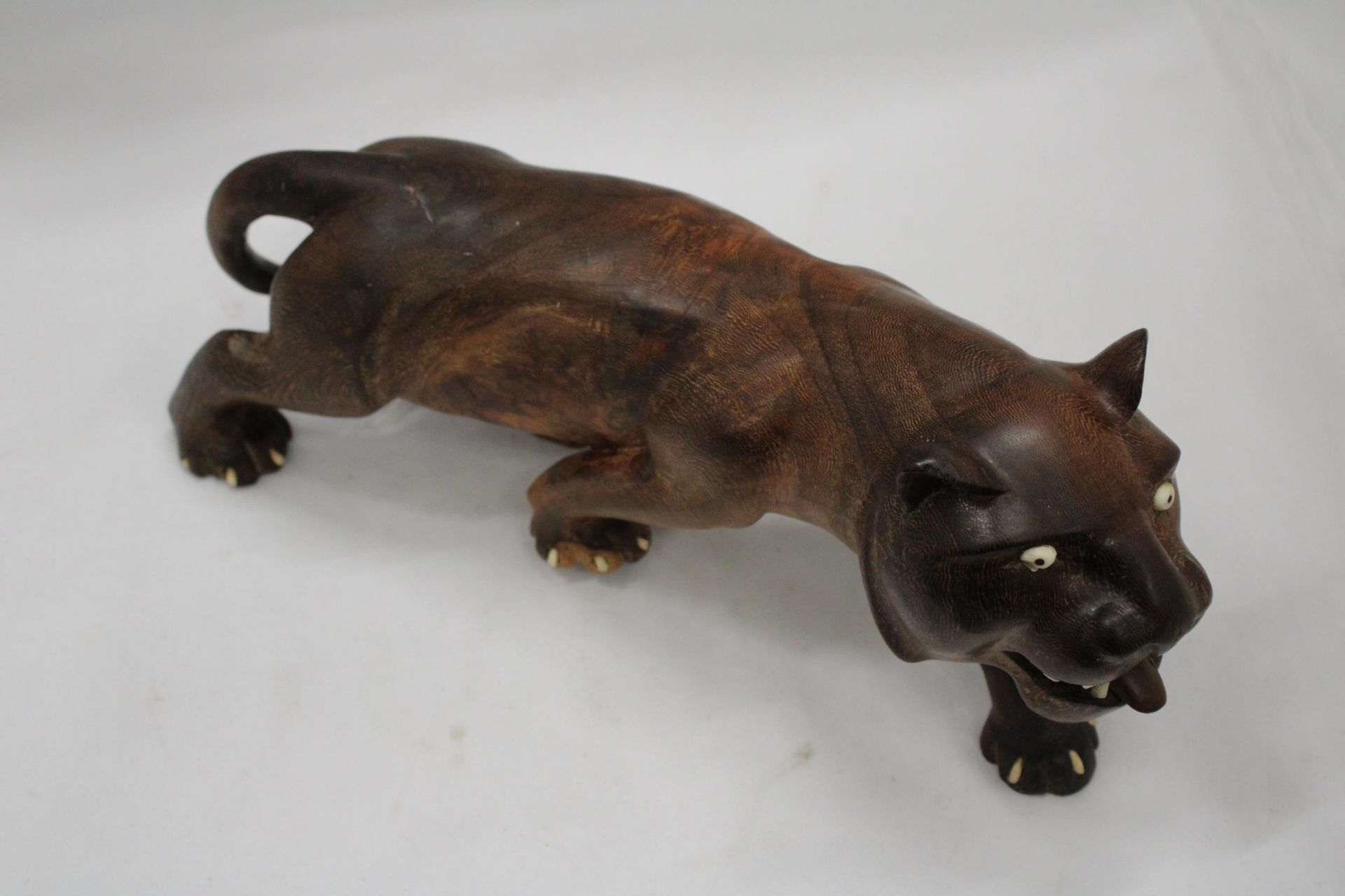 A CARVED HARD WOOD FIGURE OF A BIG CAT, HEIGHT 16CM, LENGTH 36CM