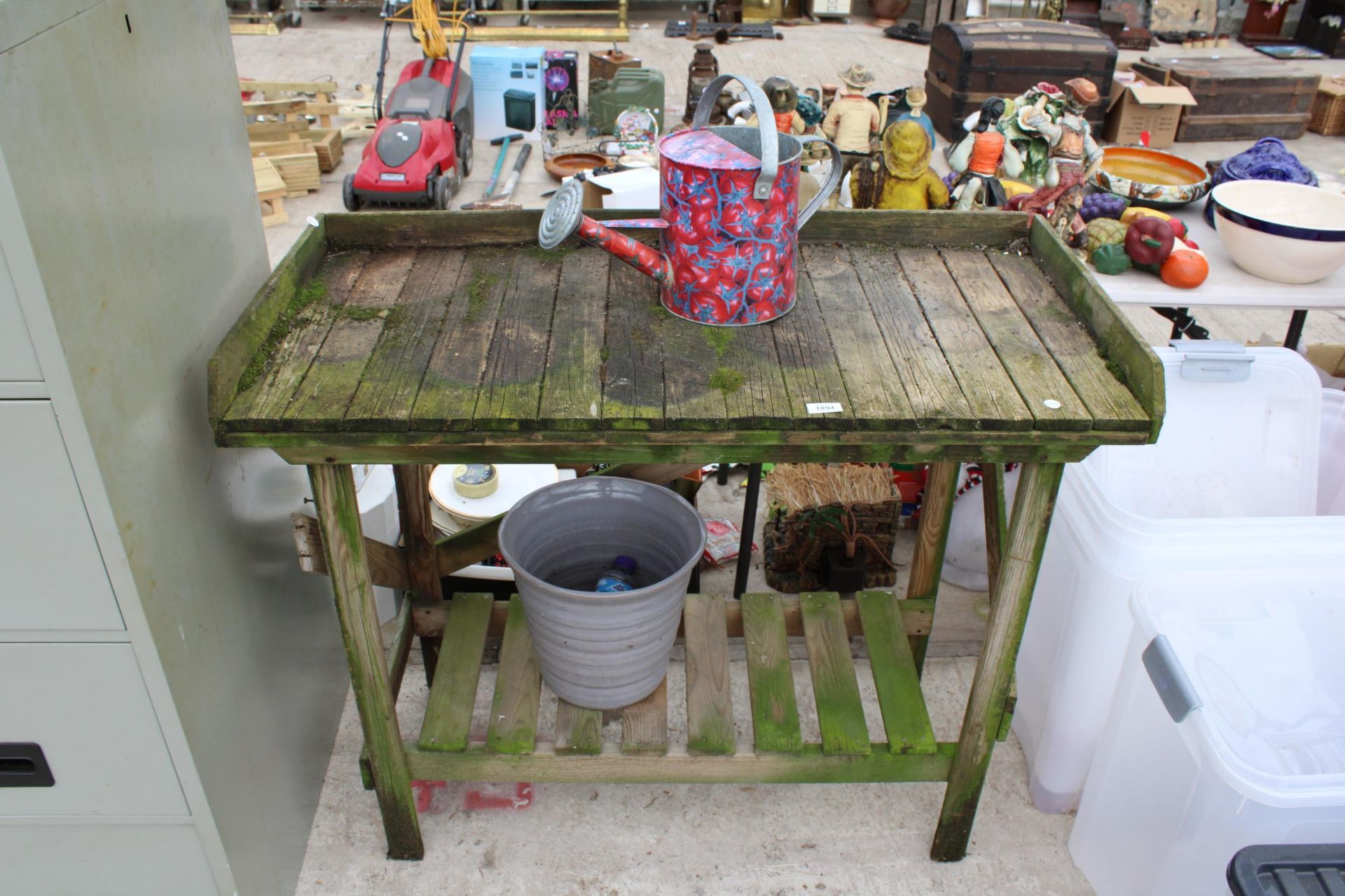 A WOODEN POTTING BENCH, A WATERING CAN AND A PLANT POT