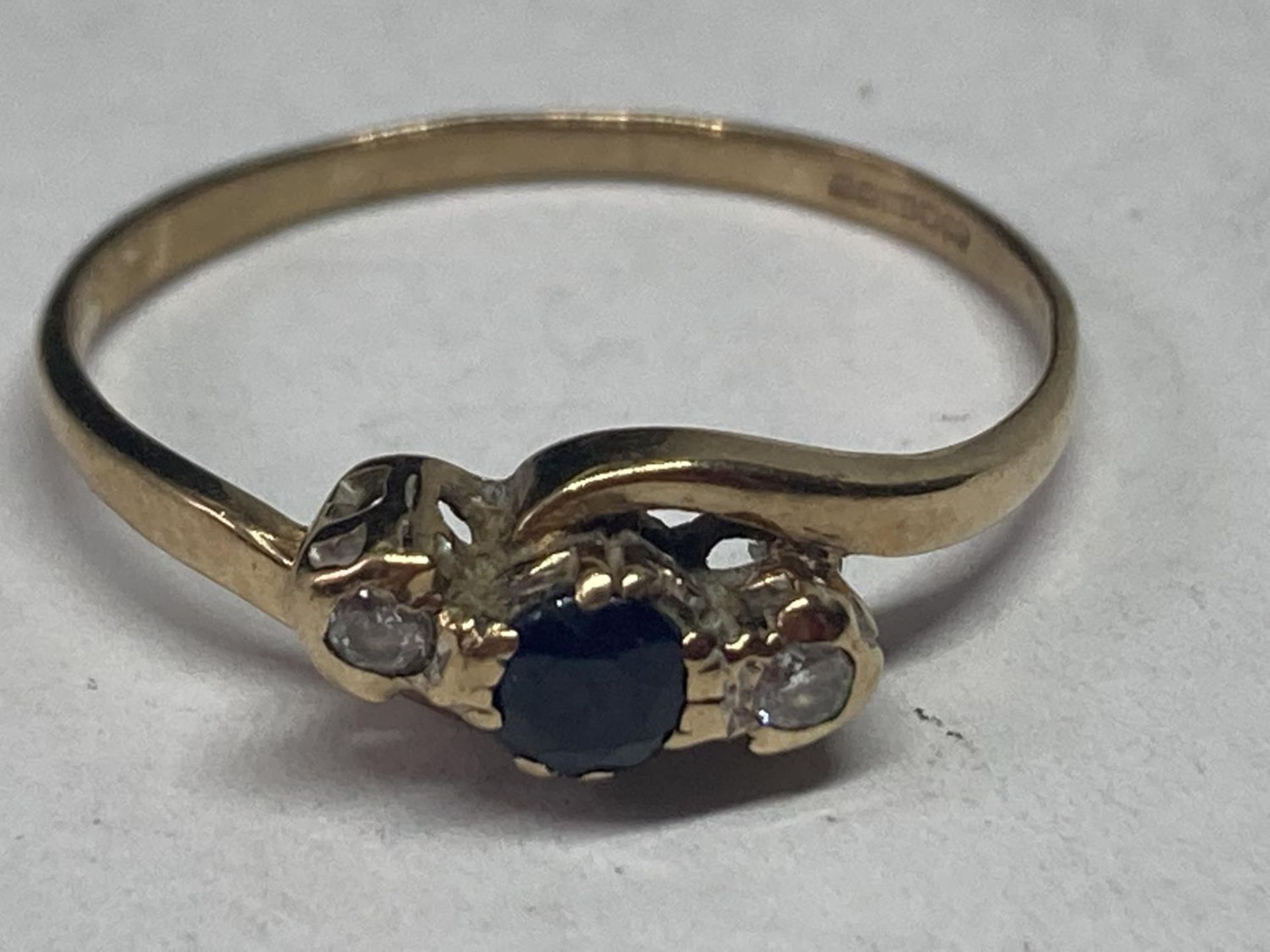 A 9 CARAT GOLD RING WITH A CENTRE SAPPHIRE AND TWO DIAMONDS SIZE N/O