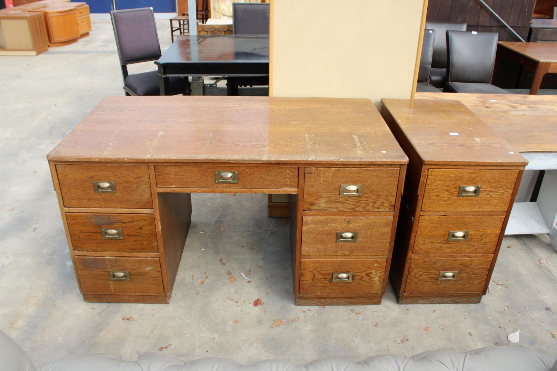 A MID TWENTIETH CENTURY OAK TWIN PEDESTAL DESK ENCLOSING SEVEN DRAWERS WITH BRASS HANDLES, 56" X