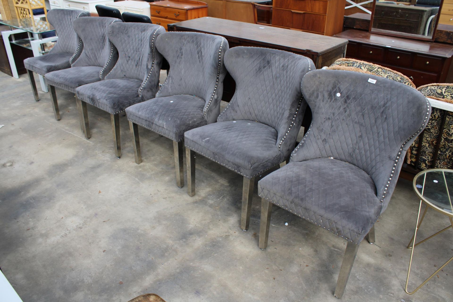 A SET OF SIX MODERN WINGED DINING CHAIRS ON POLISHED CHROME LEGS WITH LION MASK HANDLES TO BACKS