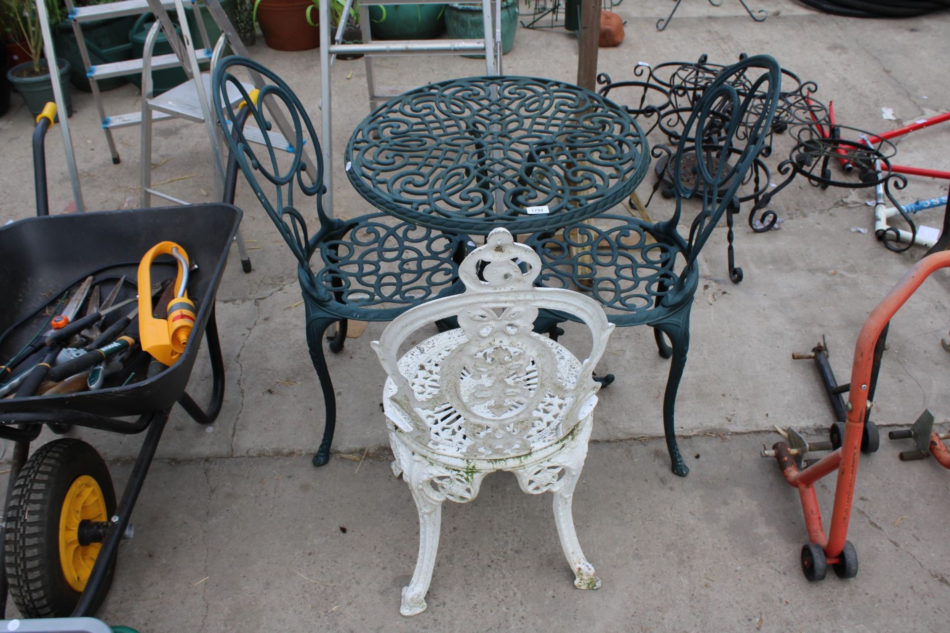 A METAL BISTRO TABLE AND TWO CHAIRS AND A FURTHER CAST ALLOY BISTRO CHAIR