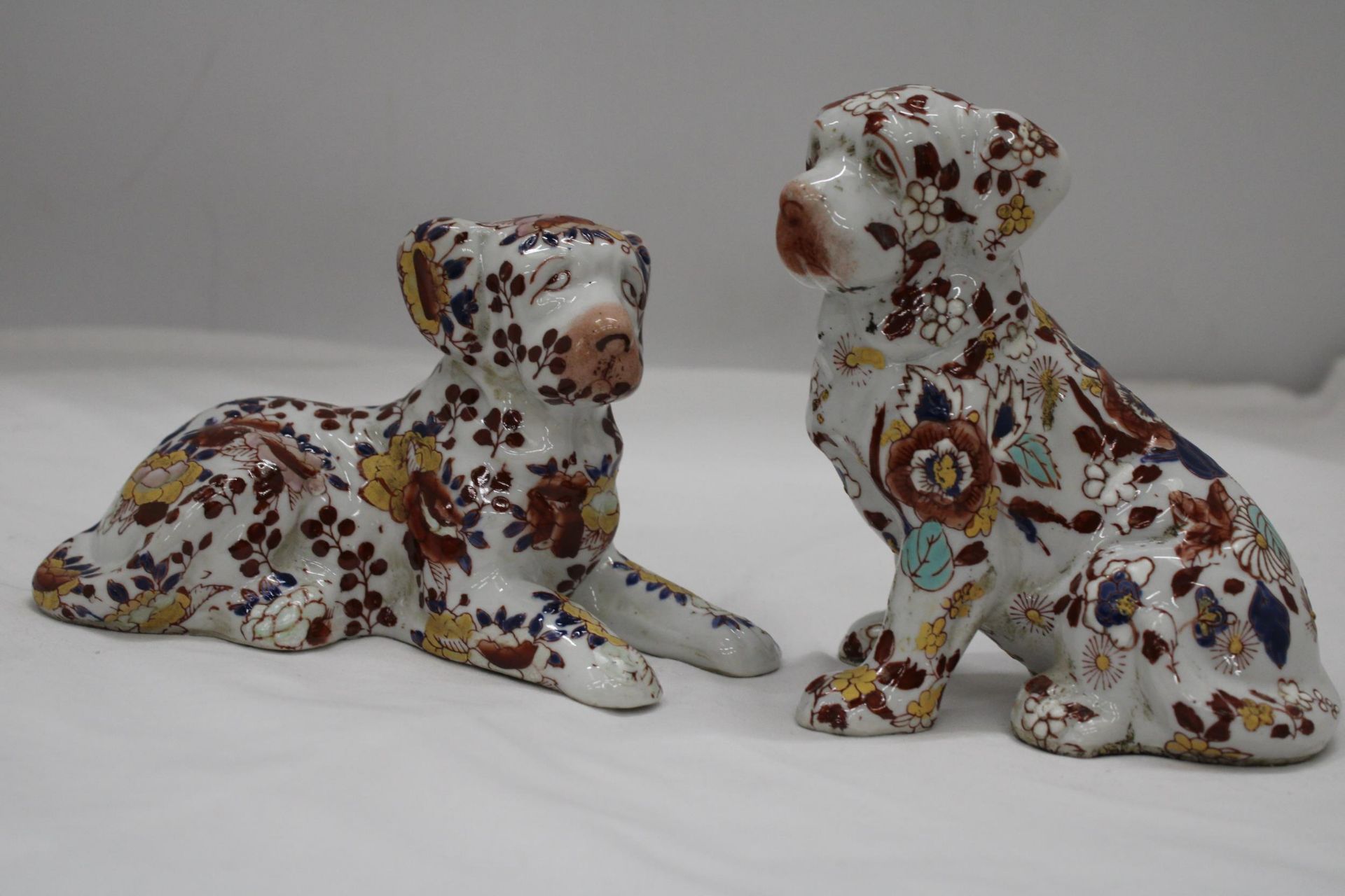 A PAIR OF FLORAL DOGS, ONE WITH ORIENTAL MARKS TO THE BASE