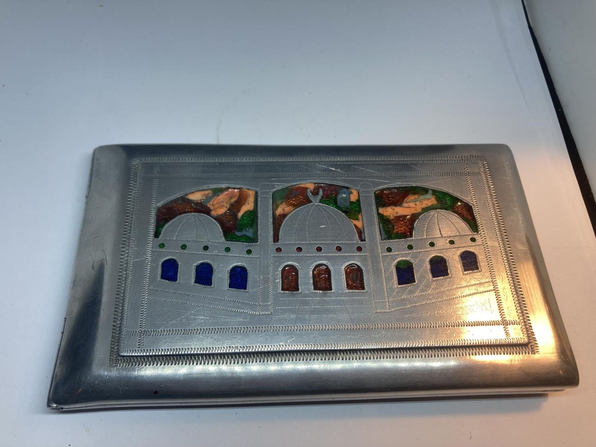 AN UNUSUAL WHITE METAL AND ENAMEL CIGARETTE CASE DEPICTING INDIA, EGYPT AND AFRICA WITH HEART SHAPED