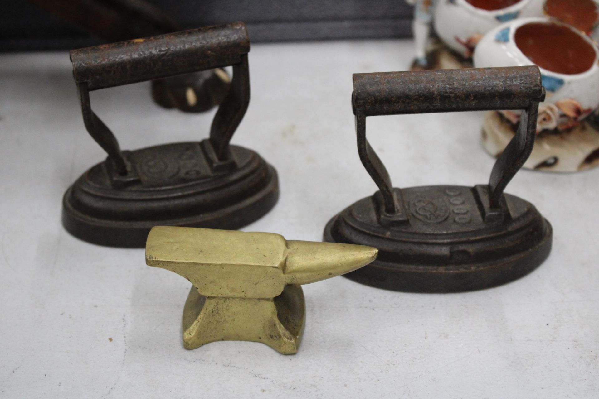 A COLLECTION OF MINIATURE ITEMS TO INCLUDE THREE IRONS, A BRASS ANVIL AND A 'LADY' BELL - Image 4 of 4