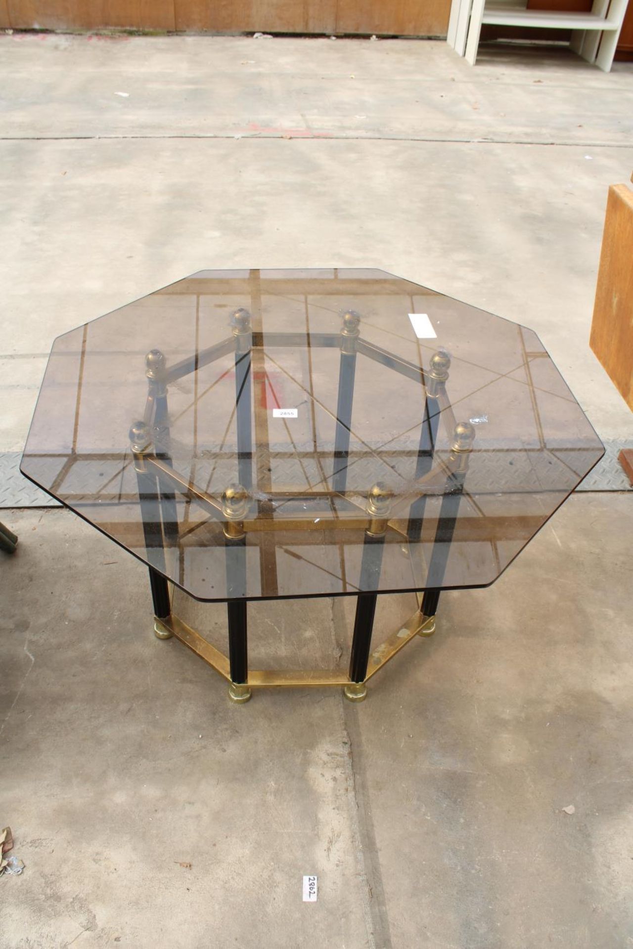 A RETRO OCTAGONAL SMOKED GLASS COFFEE TABLE ON BLACK AND BRASS EFFECT BASE