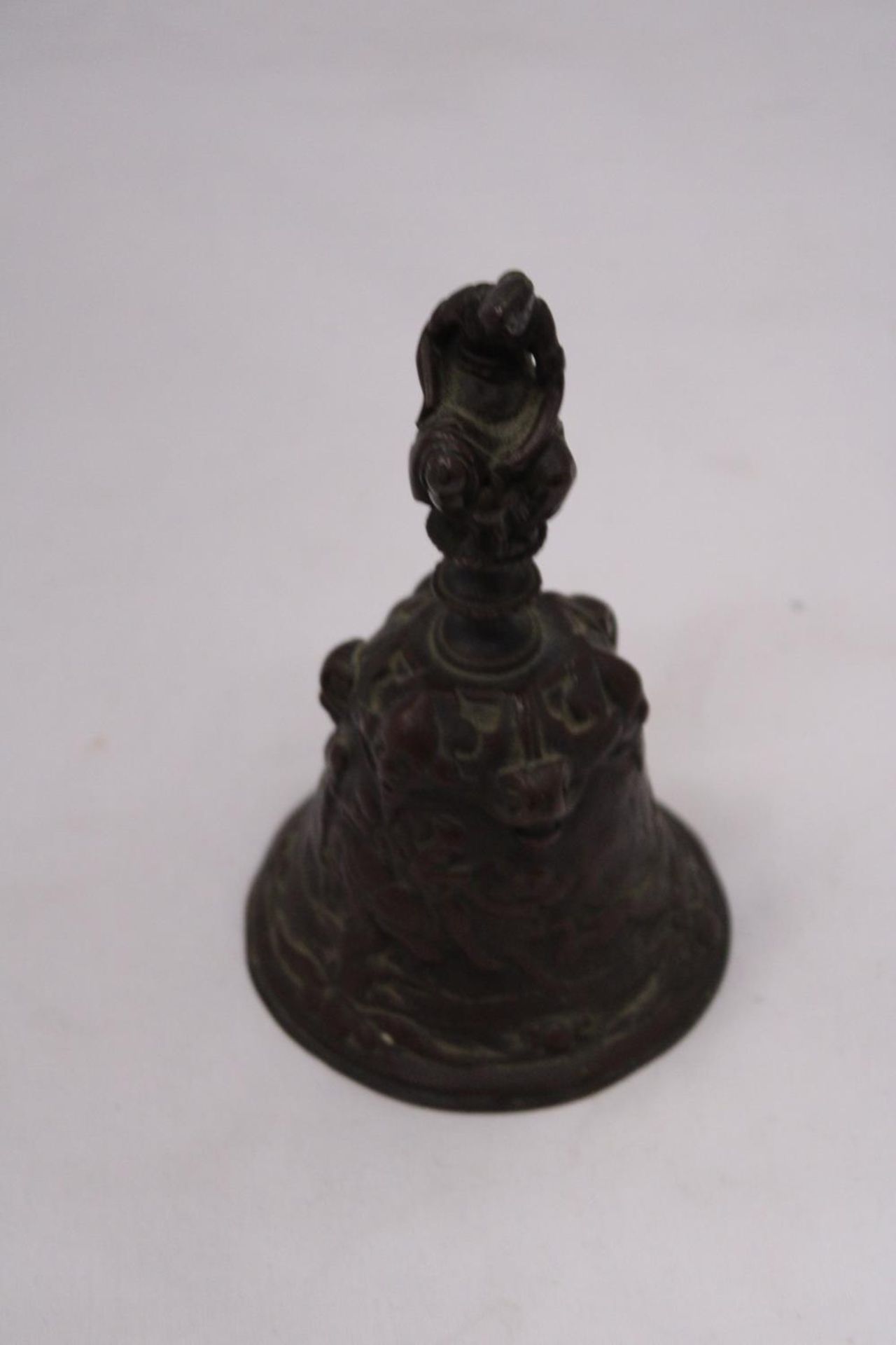 A ORIENTAL BRONZE BELL DEPICTING A HUNTING SCENE AROUND BASE OF BELL
