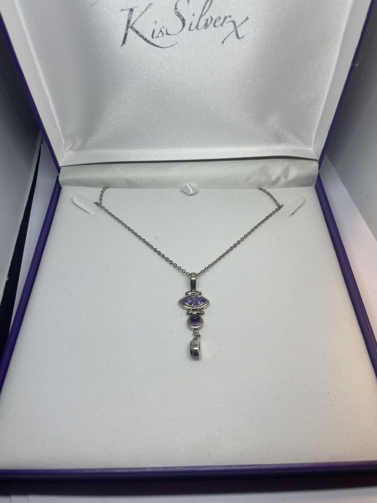 A SILVER NECKLACE IN A PRESENTATION BOX