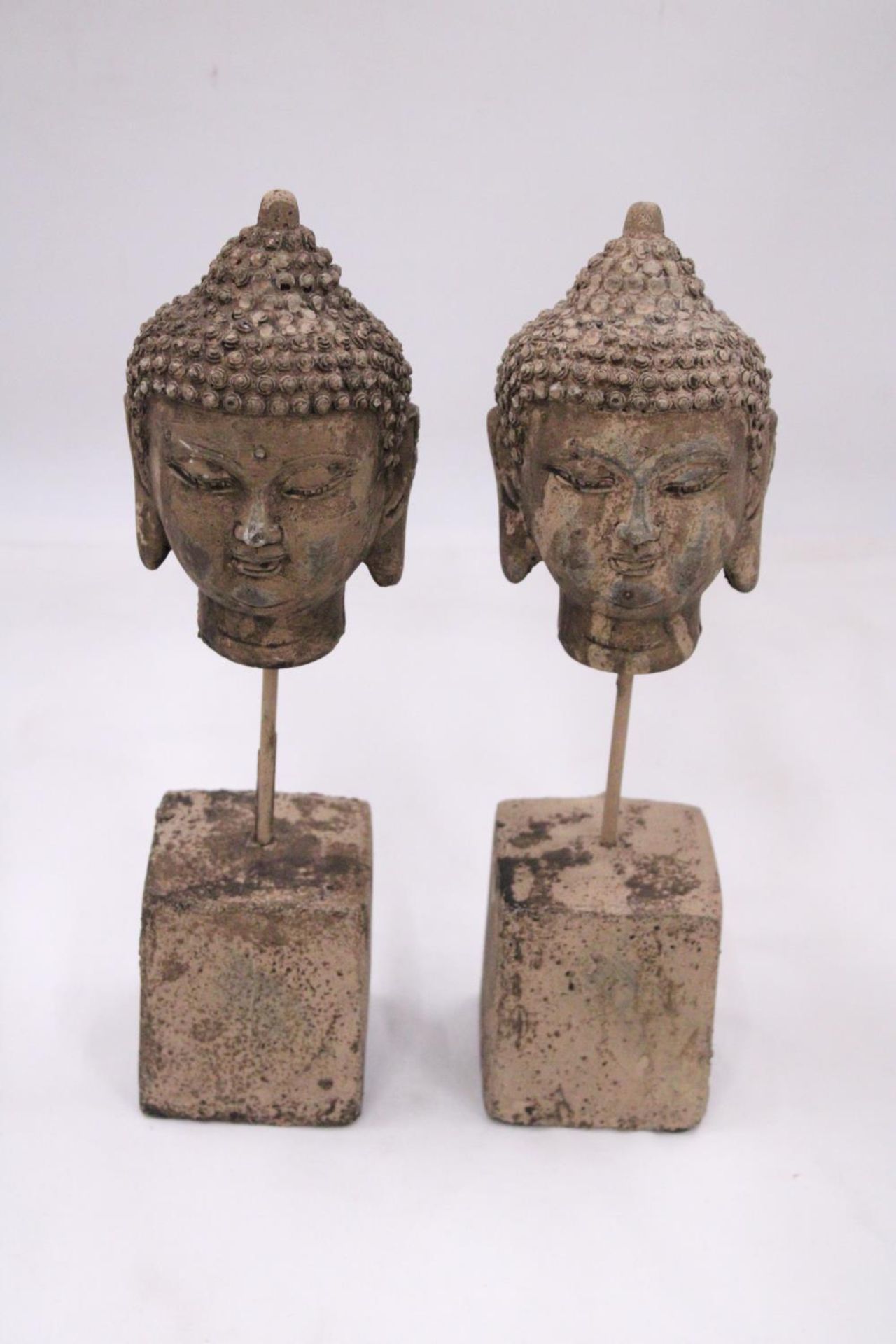 A PAIR OF STONE BUDDHA HEADS ON STANDS