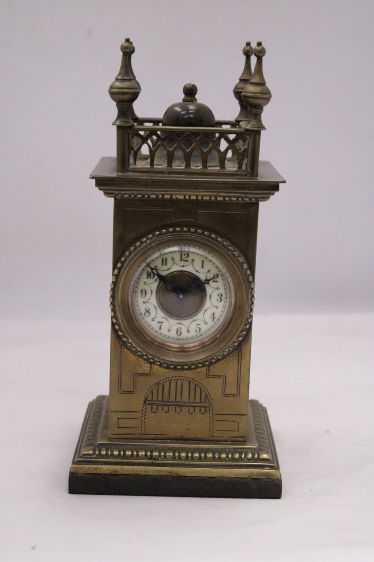 A VINTAGE BRASS MANTEL CLOCK ON A MARBLE BASE, WITH FOUR SPIRES TO THE TOP. WORKING WHEN