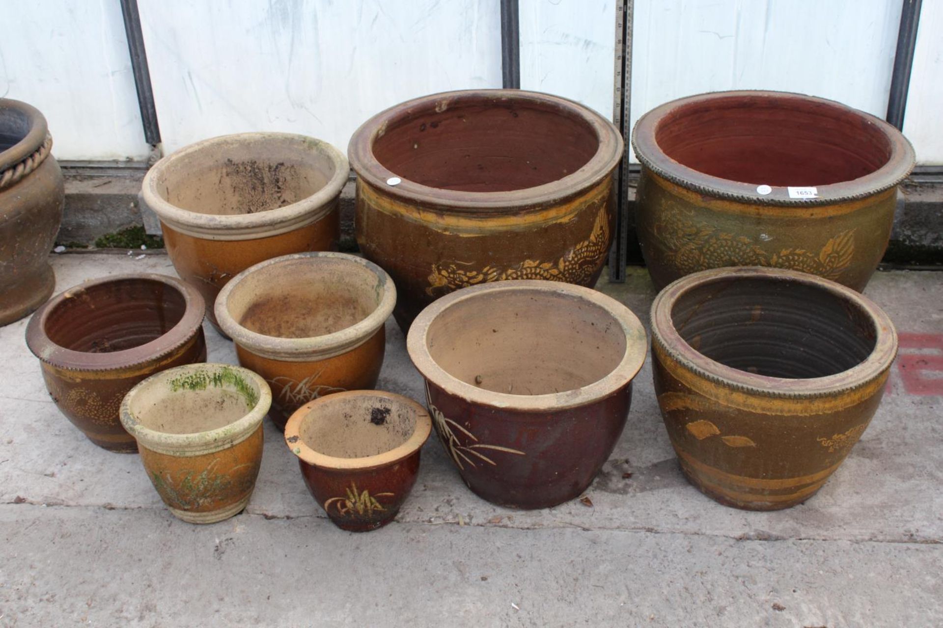 AN ASSORTMENT OF VARIOUS SIZED BROWN GLAZED GARDEN POTS, SOME DEPICTING DRAGONS