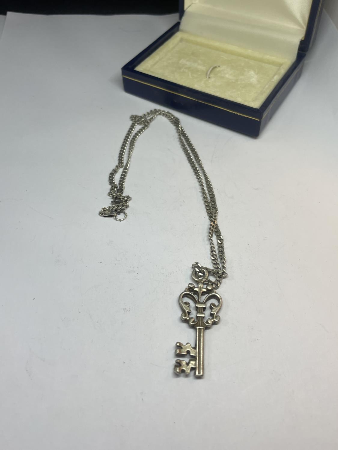 A SILVER KEY NECKLACE IN A PRESENTATION BOX