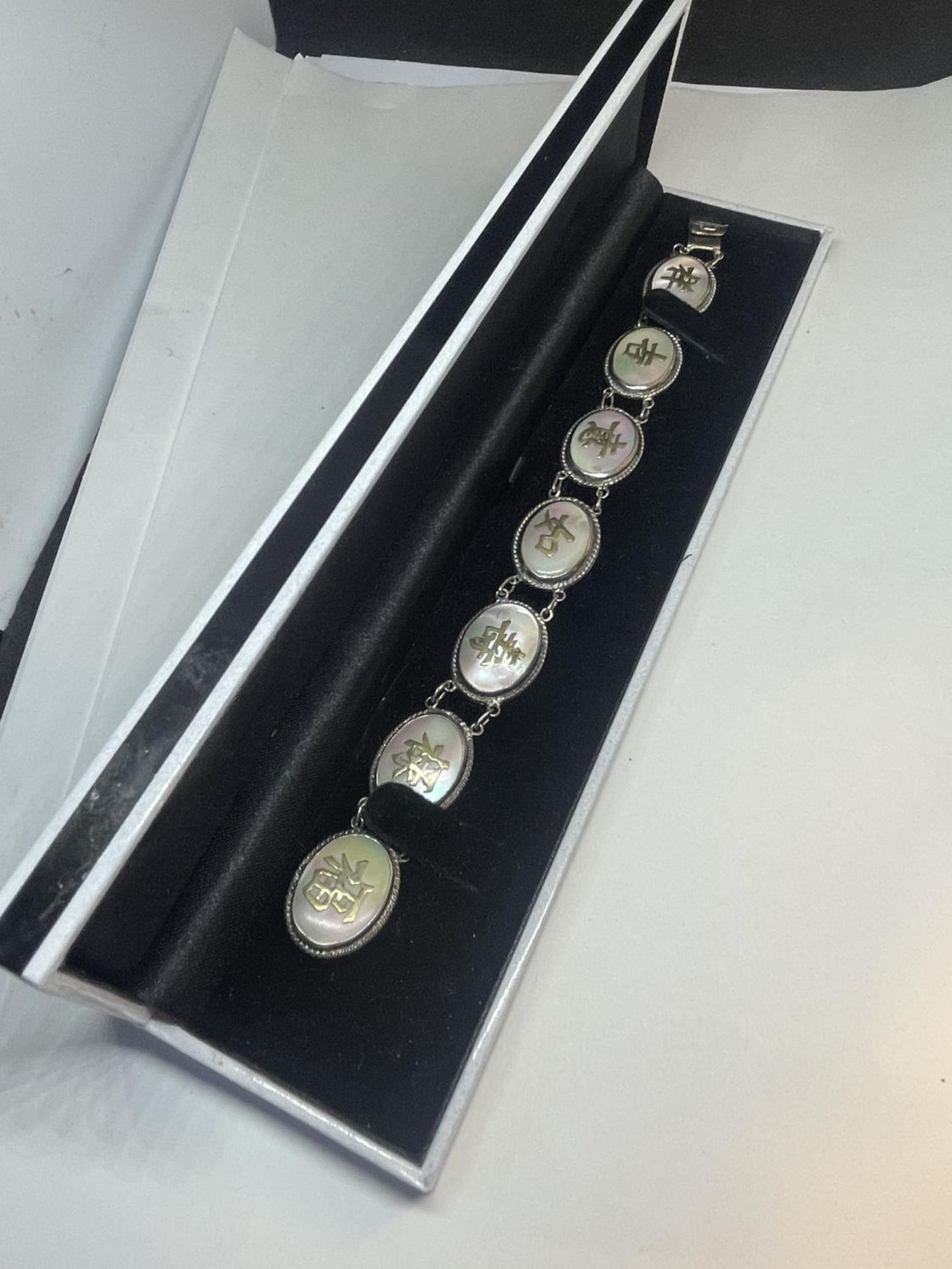 AN ORIENTAL SILVER AND MOTHER OF PEARL CHARACTER LINK BRACELET IN A PRESENTATION BOX