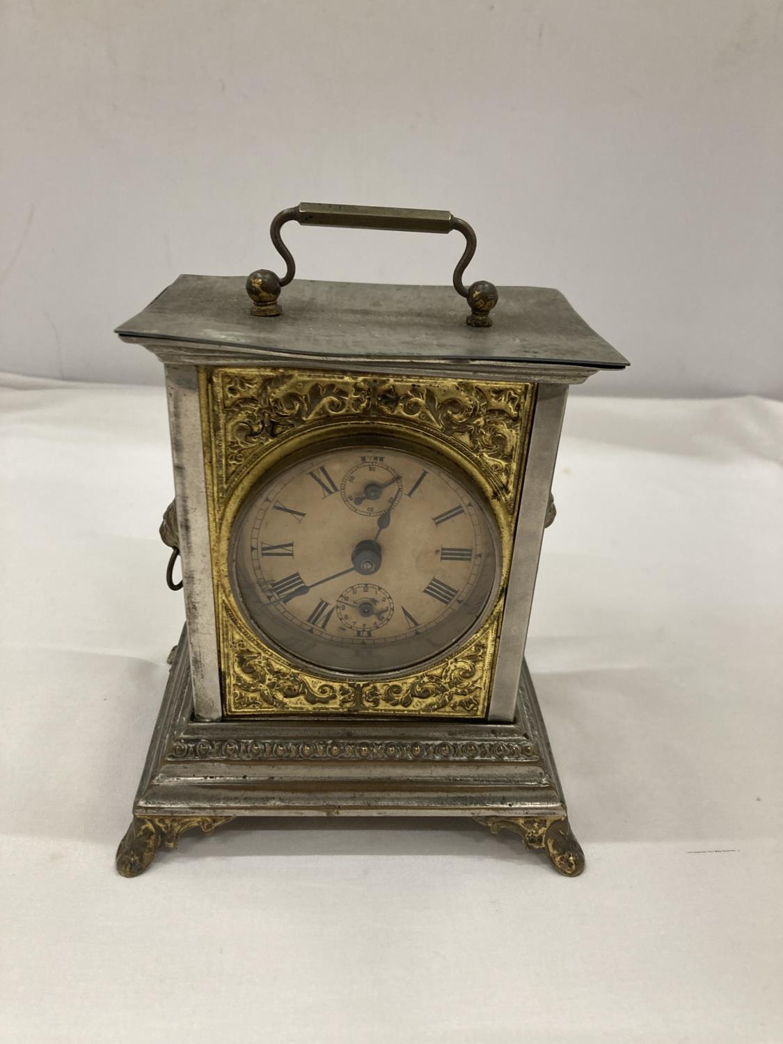 AN OFFICER'S ALARM CLOCK WITH BRASS DECORATION AND LION HEADS TO THE SIDE