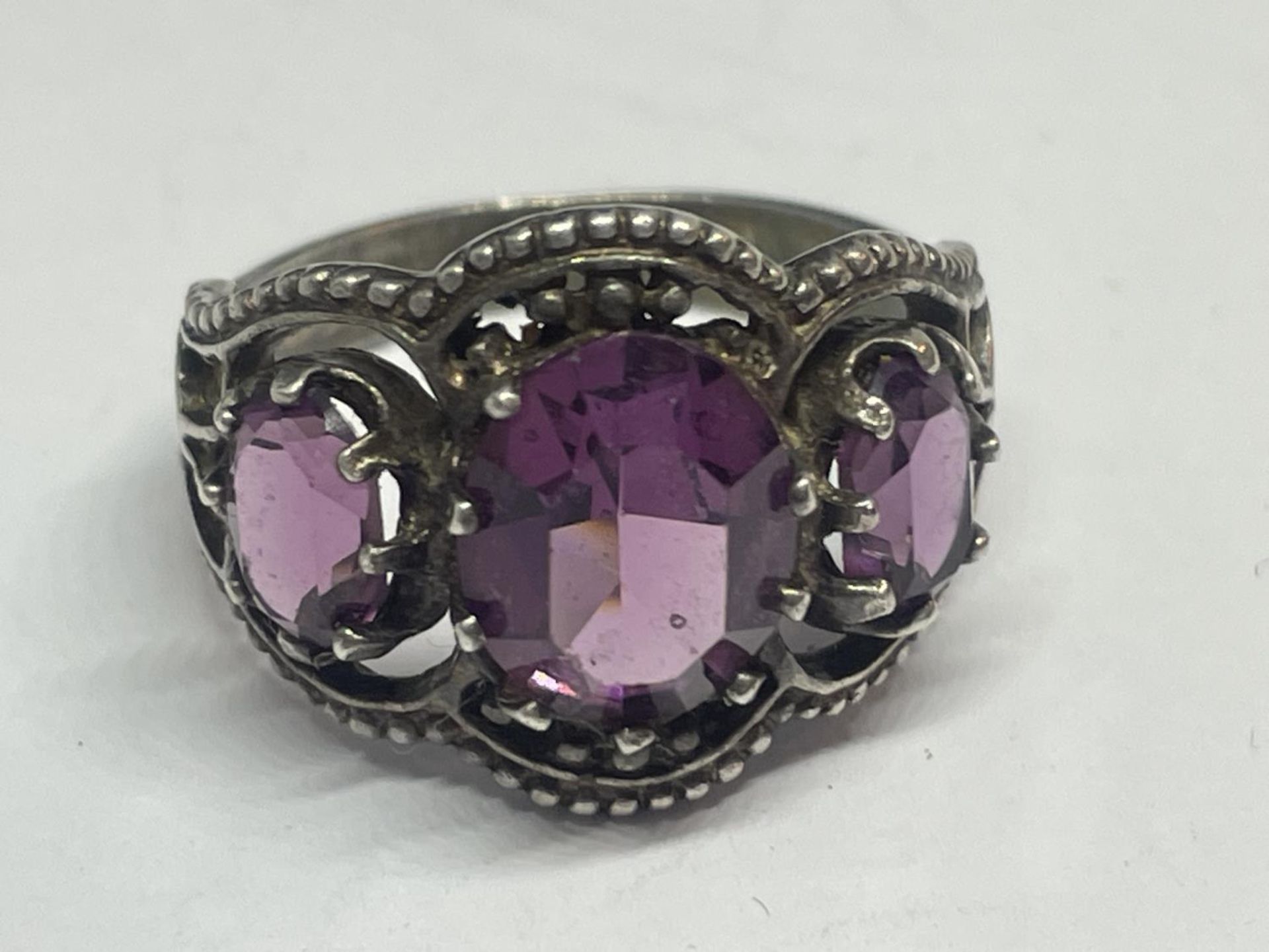 A SILVER RING WITH AMETHYST COLOURED STONES