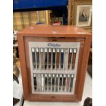 A LARGE REVOLVING SQUARE WATCH STRAP DISPLAY CABINET WITH DRAWERS CONTAINING STRAPS