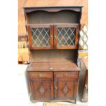 AN OAK DRESSER WITH PLATE RACK ENCLOSING 2 GLAZED AND LEADED DOORS, 36" WIDE