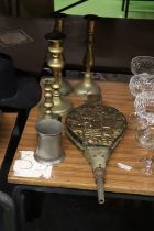 A MIXED LOT OF BRASSWARE TO INCLUDE FOUR CANDLE STICKS, A BRASS AND LEATHER FIRE BELLOWS PLUS A