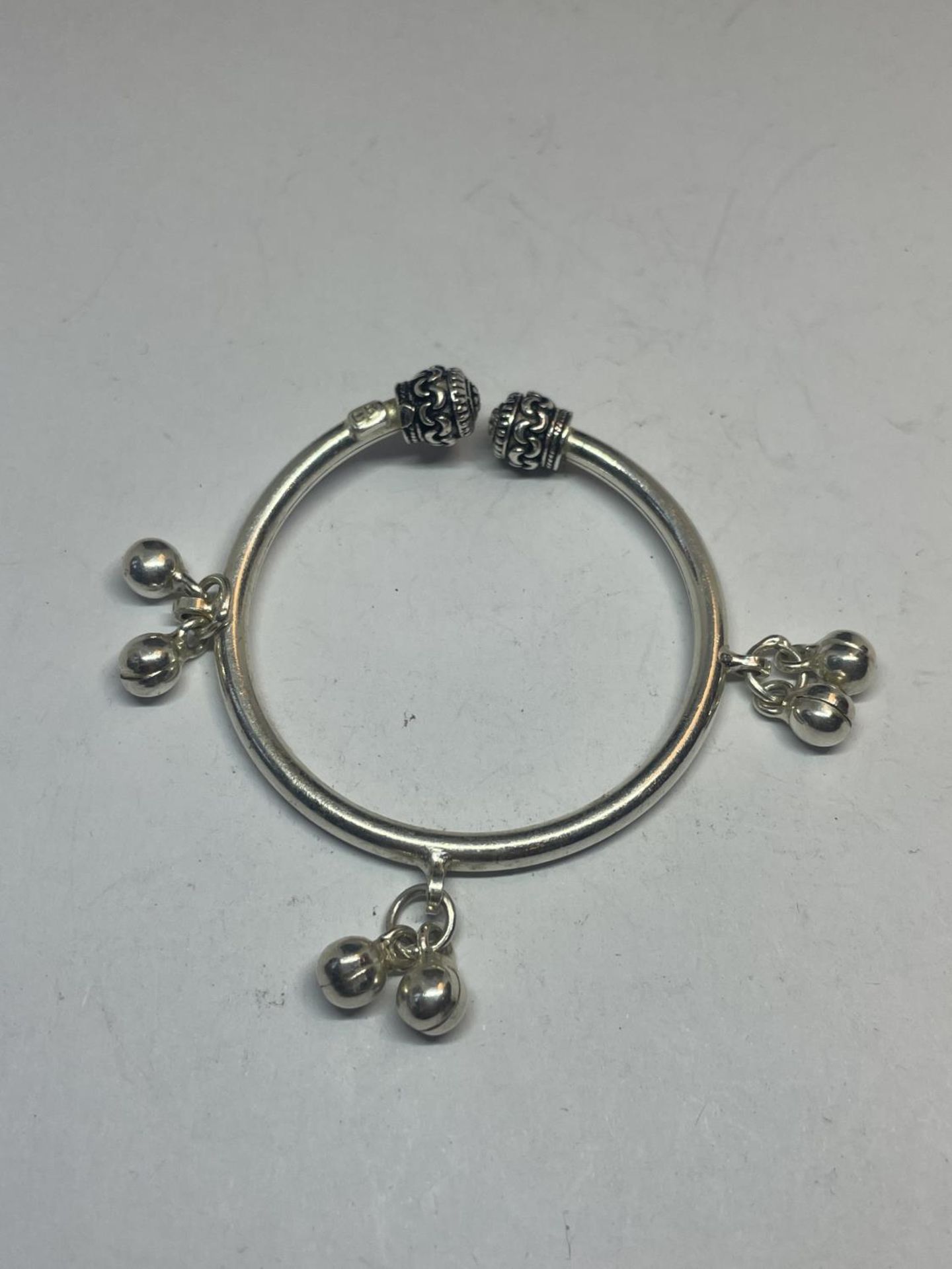 A BABY'S SILVER BANGLE WITH CHARMS