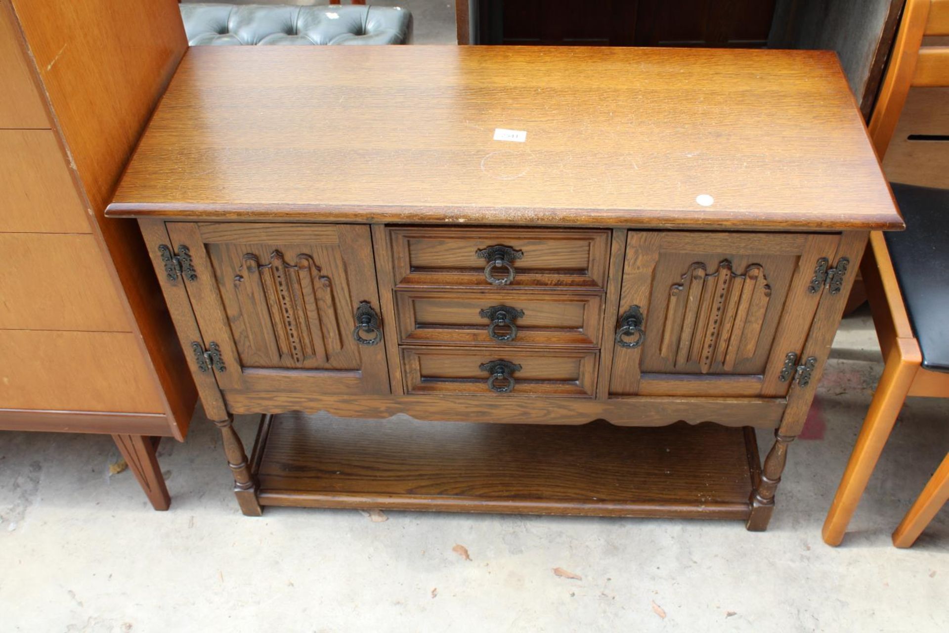 AN OAK JACOBEAN STYLE SIDE CABINET ENCLOSING 3 DRAWERS AND 2 CUPBOARDS WITH POT BOARD TO BASE ON