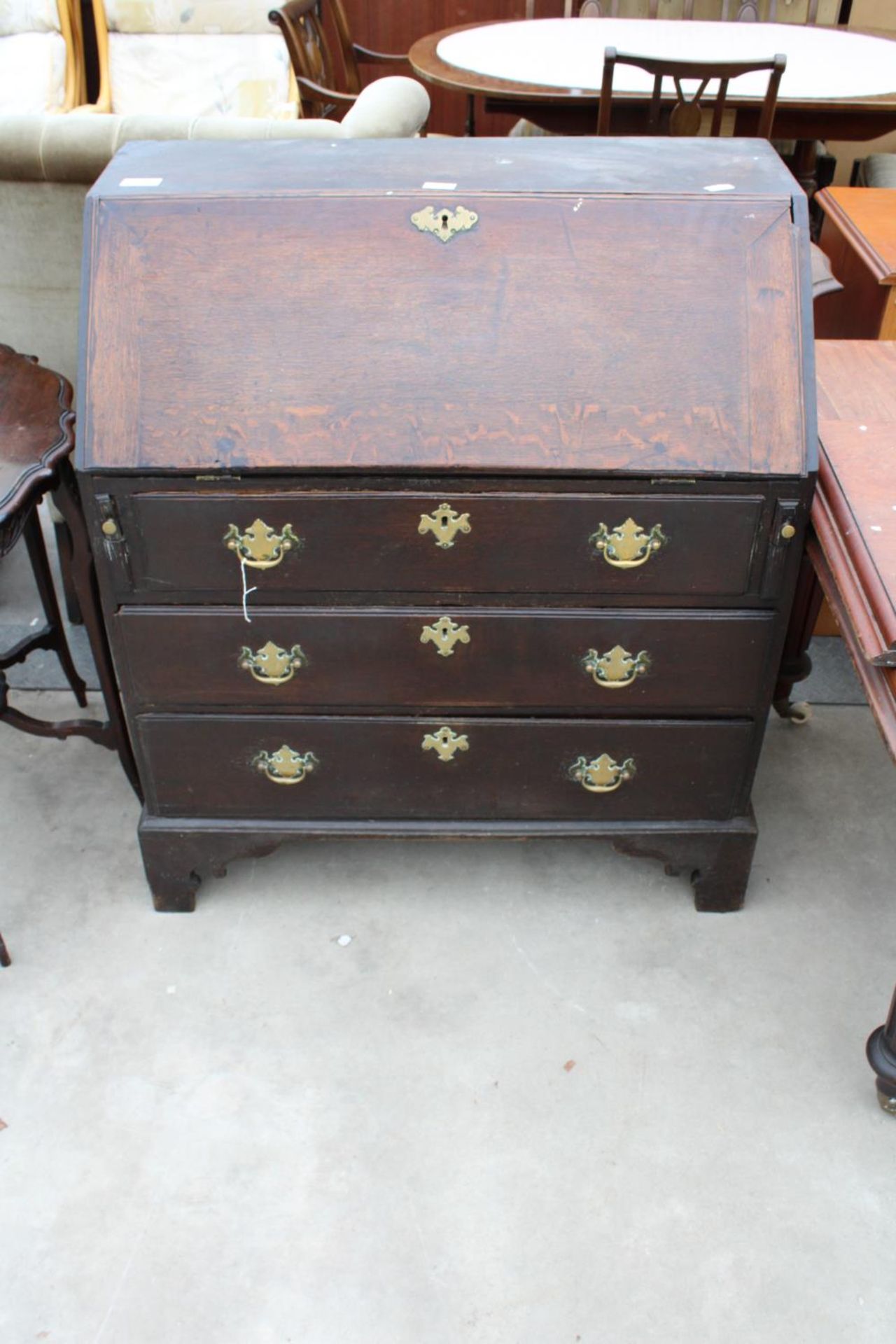 A GEORGE IV OAK BUREAU WITH FITTED INTERIORS, THREE GRADUATED DRAWERS AND BRACKET FEET, 34.5" WIDE