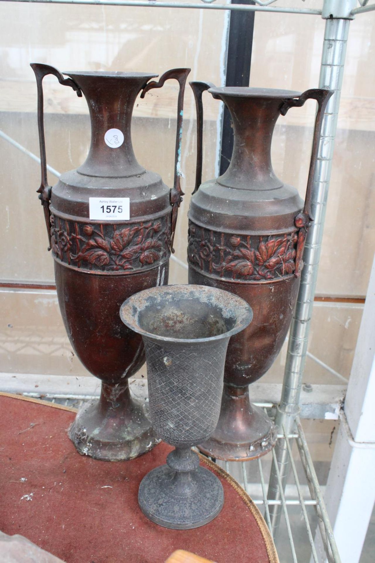A PAIR OF ORNATE AND DECORATIVE COPPER URNS AND A A FURTHER SILVER PLATED URN