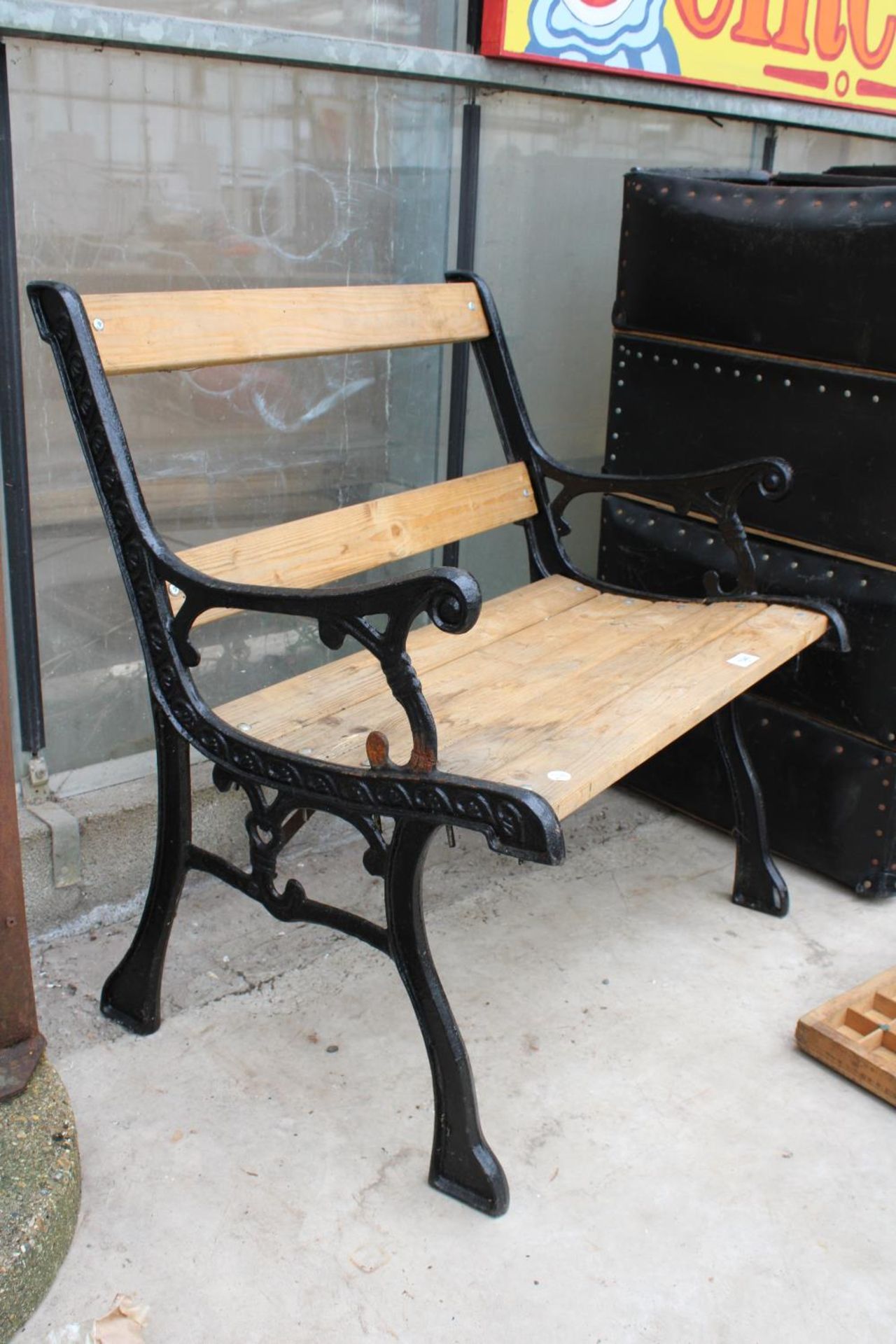 A WOODEN SLATTED CHAIR WITH CAST BENCH ENDS