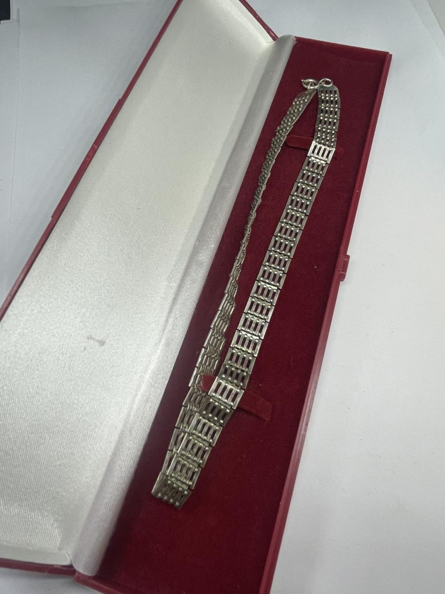 A SILVER NECKLACE IN A PRESENTATION BOX