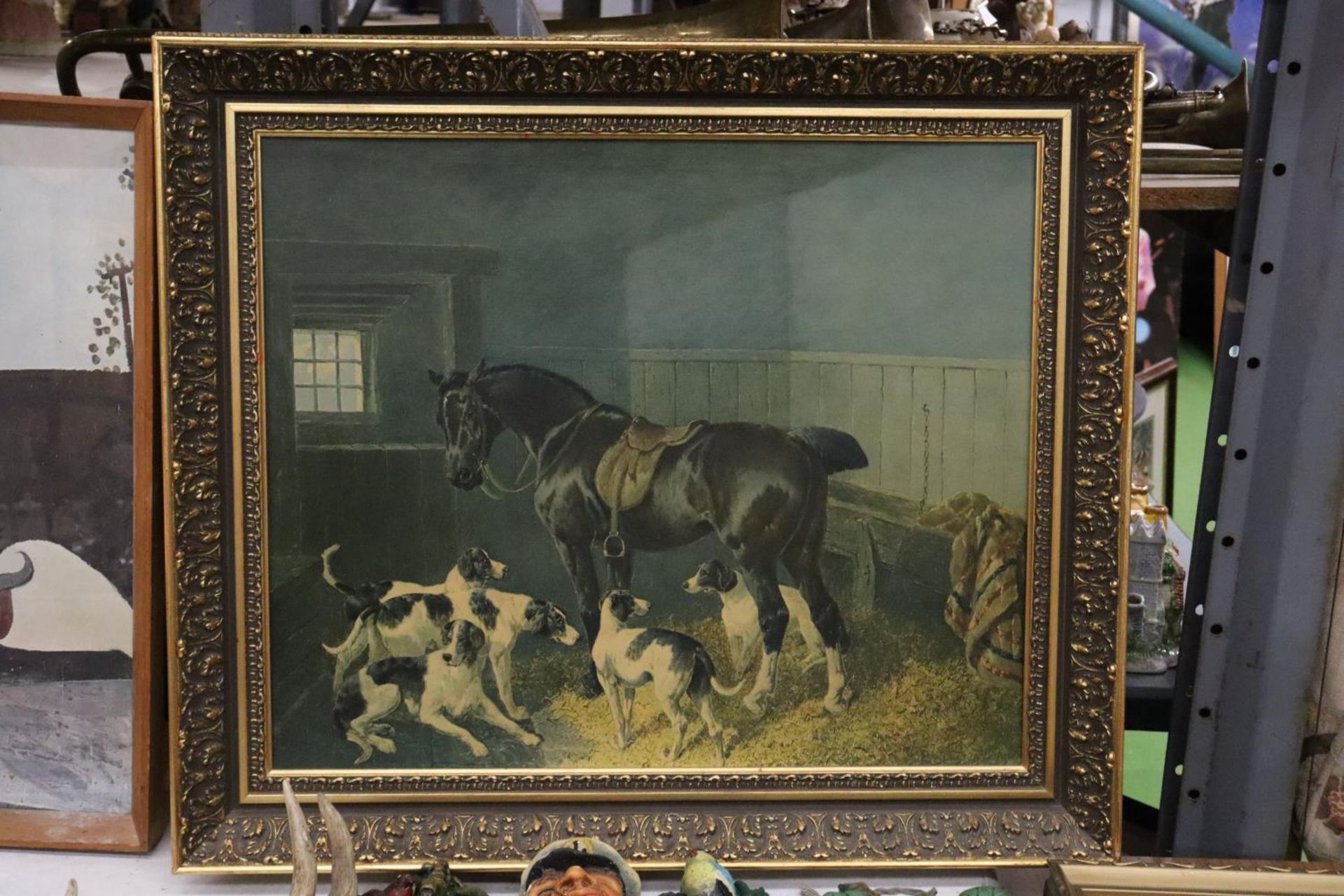 A FRAMED PRINT ON BOARD OF A HORSE AND DOGS IN A STABLE SETTING