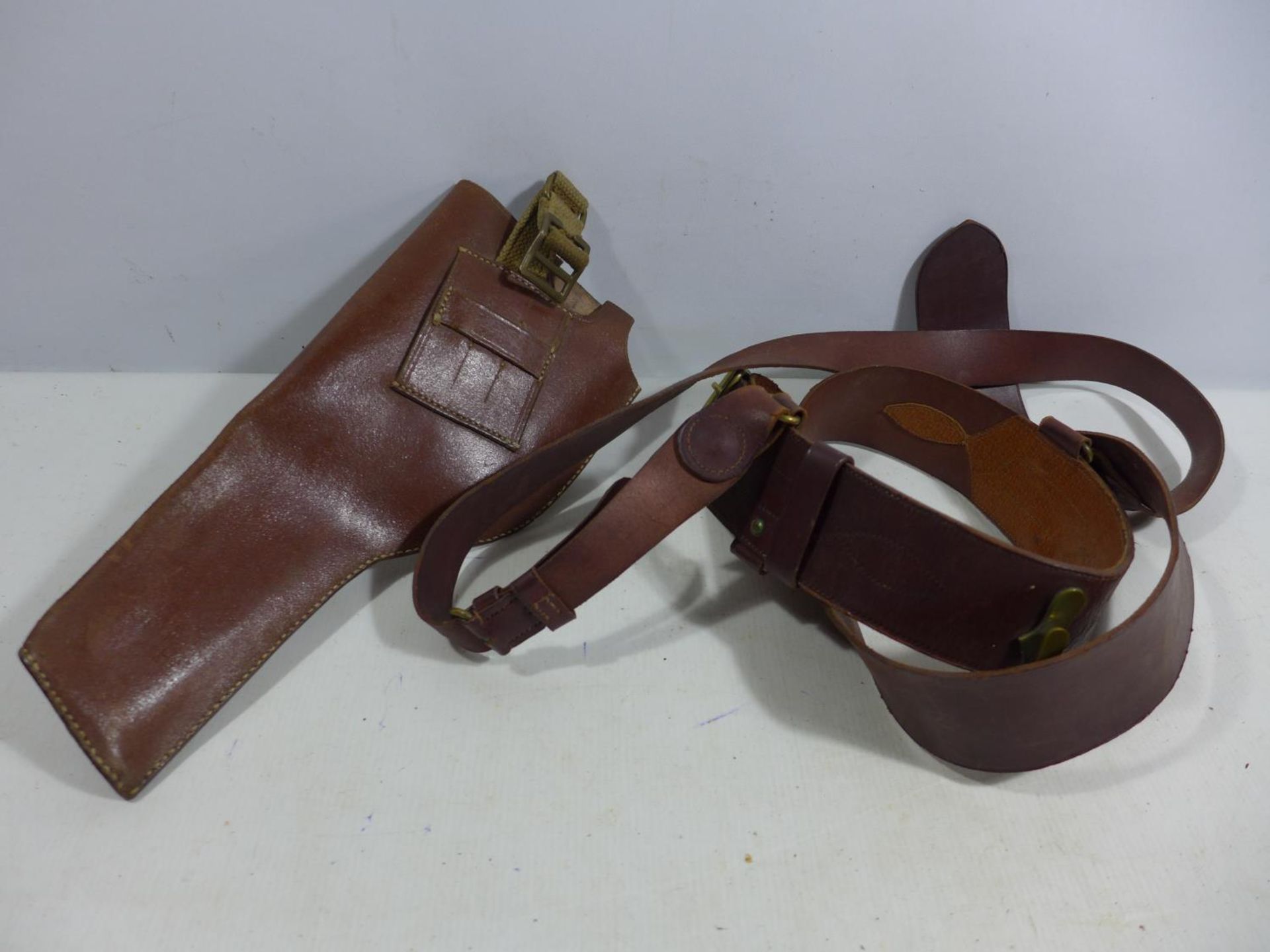 A MILITARY BROWN LEATHER GUN HOLSTER AND LEATHER SAM BROWNE BELT