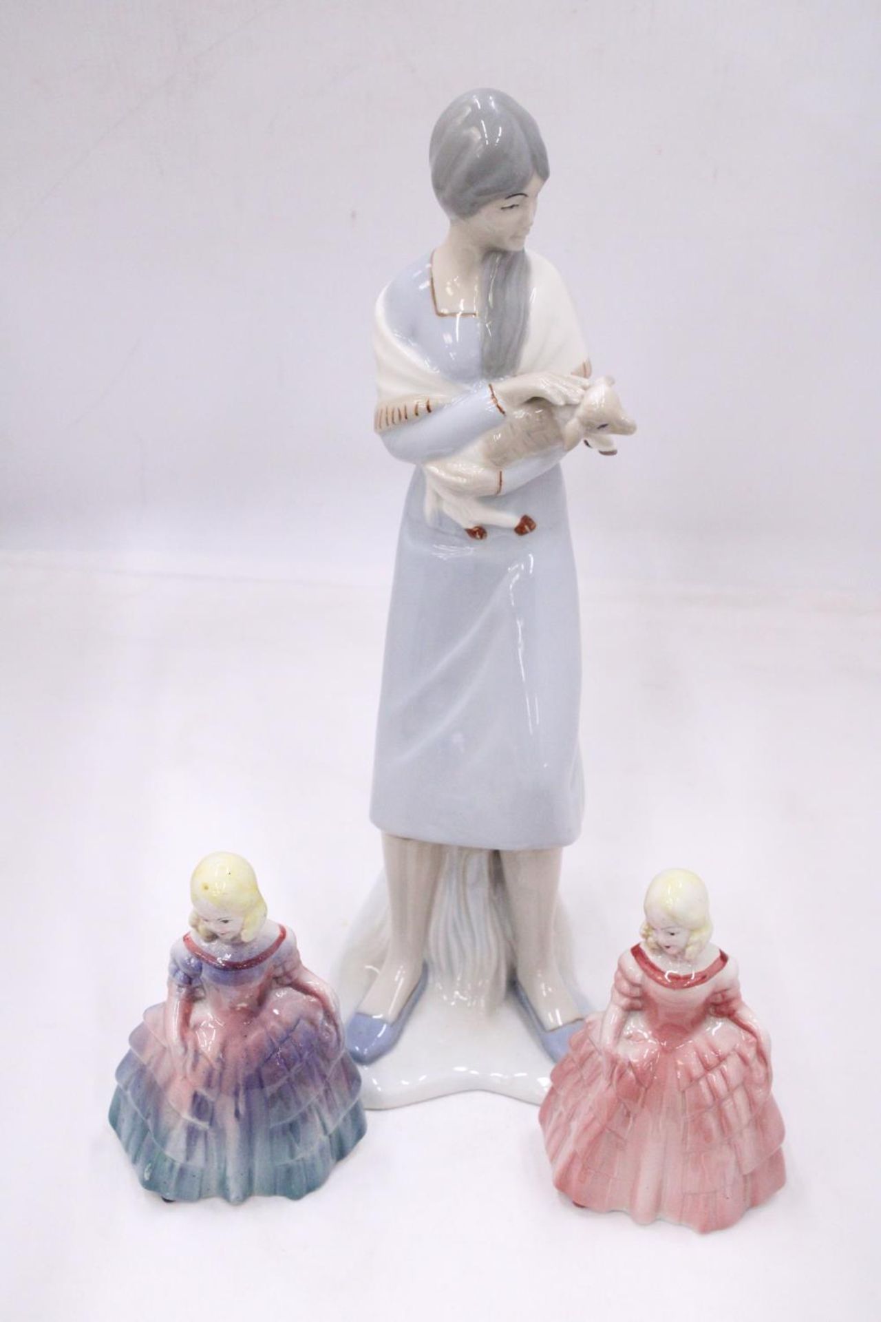 A LLADRO STYLE LADY FIGURE HOLDING A LAMB 38CM TALL, PLUS TWO ROYAL DOULTON STYLE FIGURES