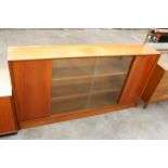 A MID CENTURY HERBERT E GIBBS, RETRO TEAK BOOKCASE WITH TWO GLASS SLIDING DOORS, WIDTH 153CM