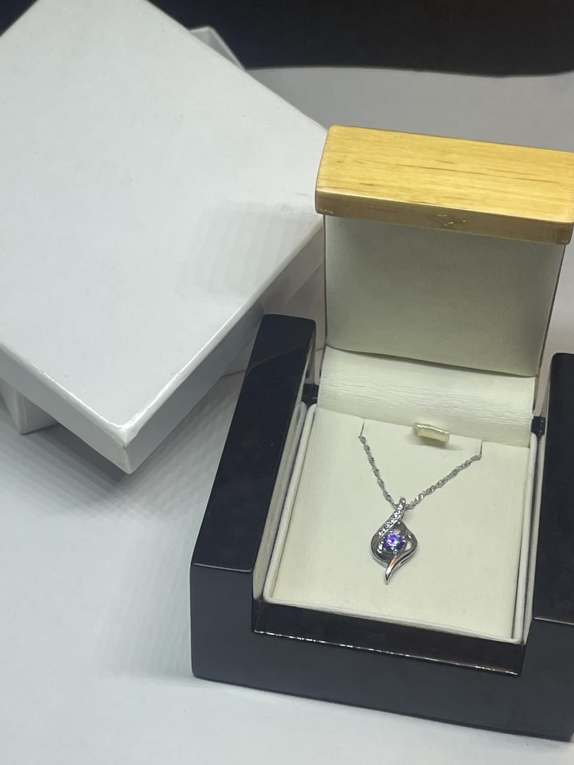 A SILVER NECKLACE IN A PRESENTATION BOX