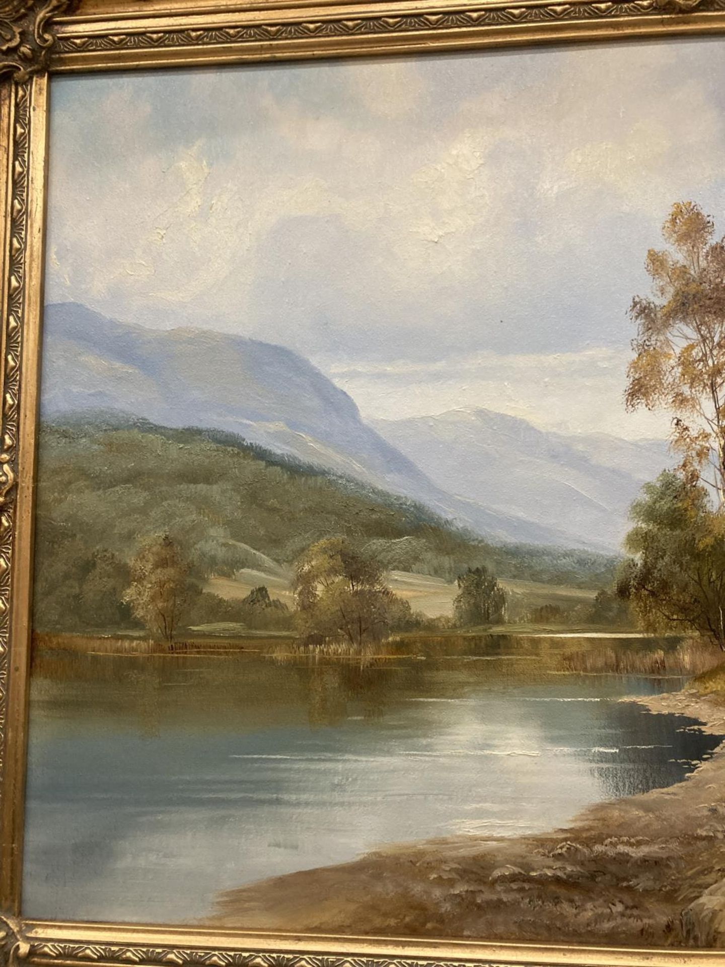 A GILT FRAMED OIL ON CANVAS OF A LAKE SCENE WITH A FARMER MOVING STOCK ...