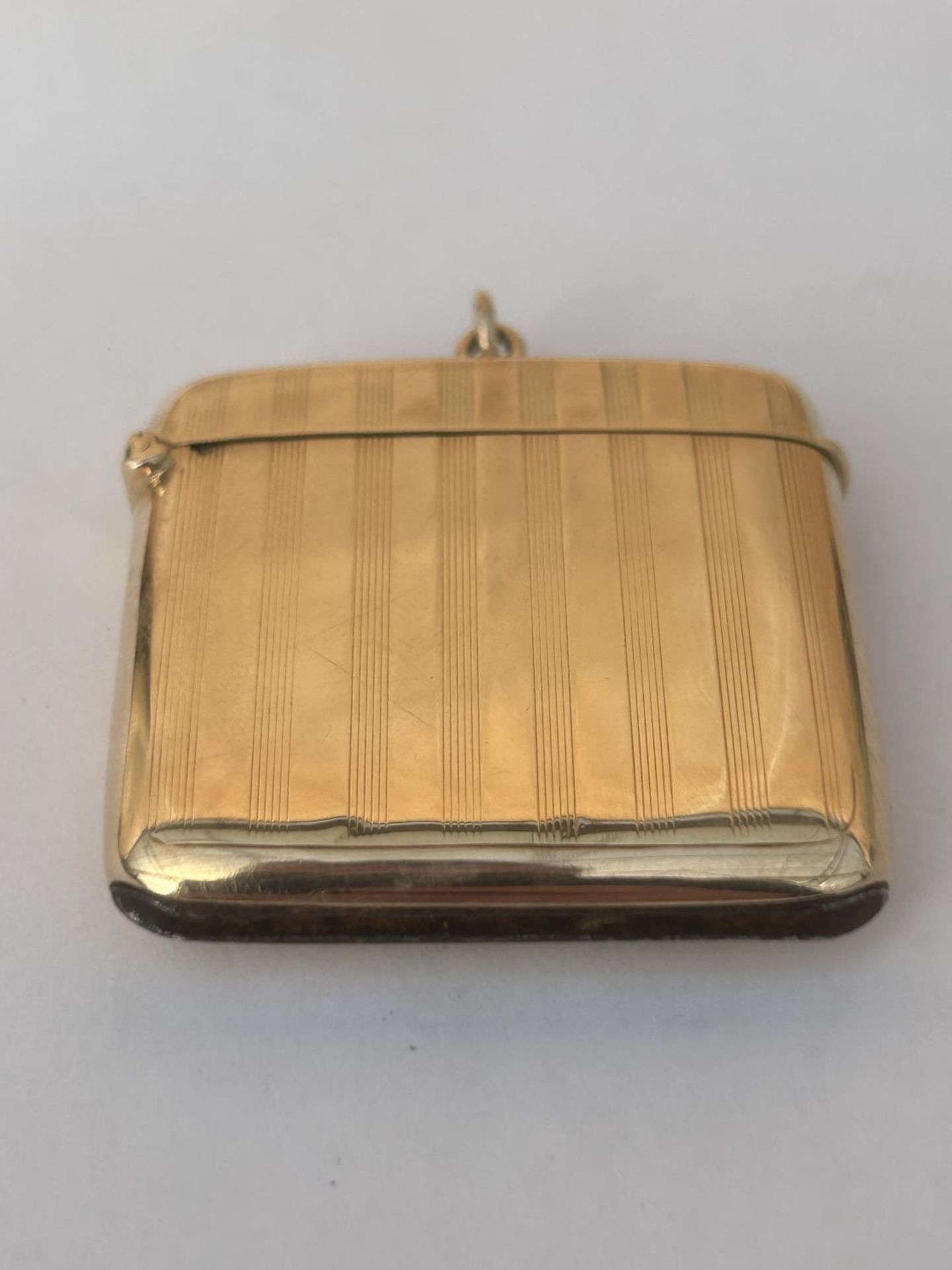 A 9CT GOLD FULLY HALLMARKED ENGINE TURNED VESTA CASE WITH FLIP TOP COVER & SUSPENSION LOOP WEIGHT