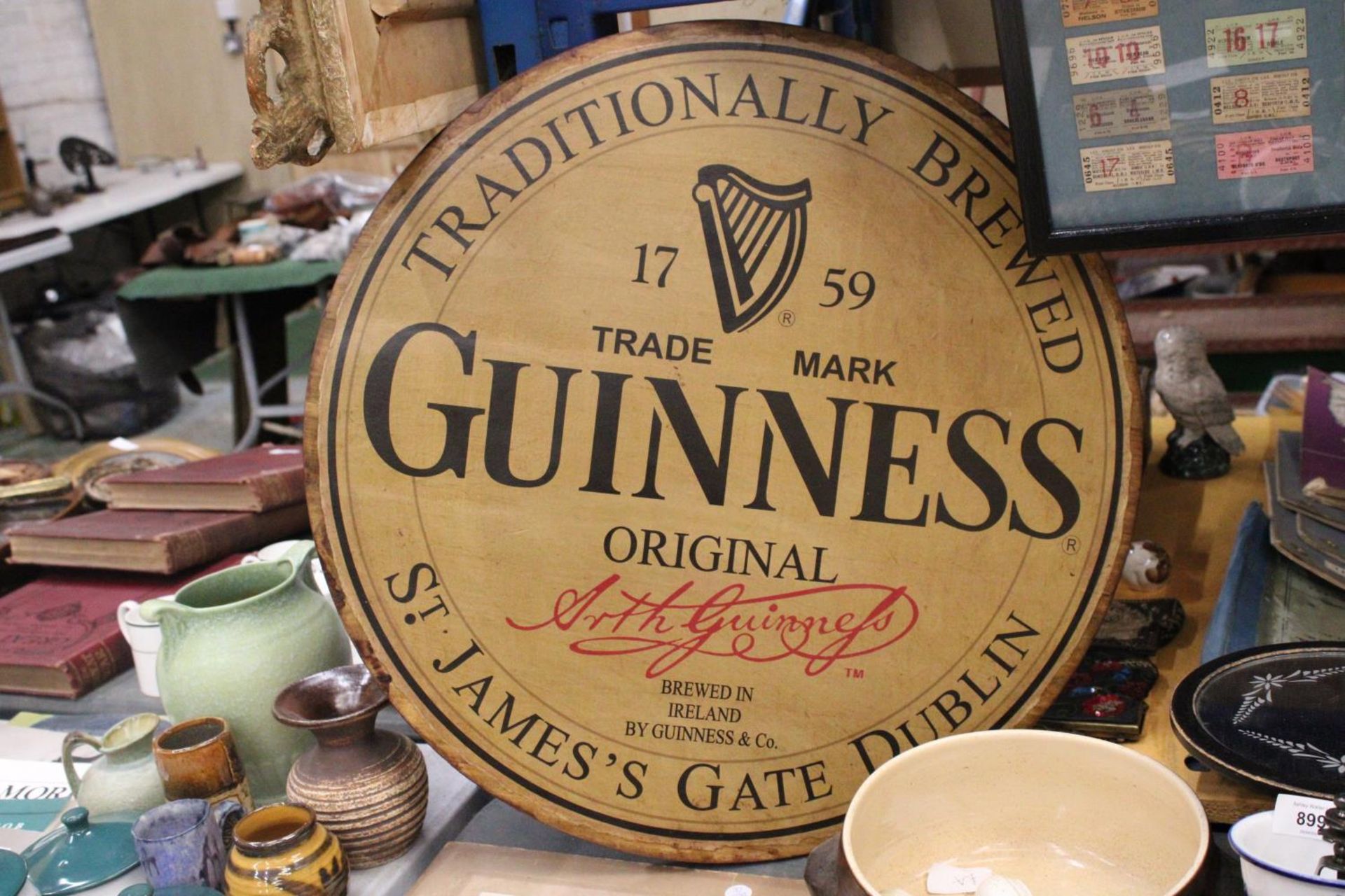 A LARGE WOODEN CIRCULAR GUINESS ADVERTISING SIGN 24" DIAMETER