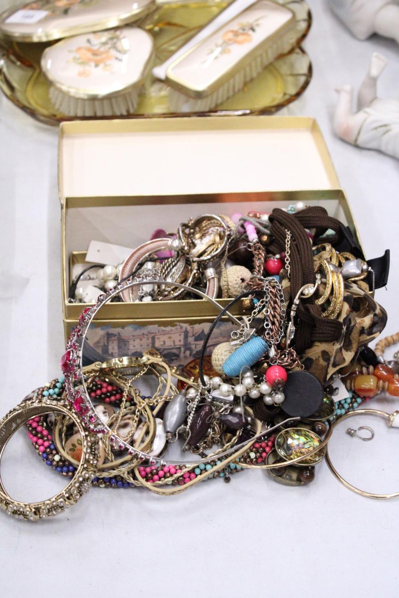 A QUANTITY OF COSTUME JEWELLERY TO INCLUDE NECKLACES, EARRINGS, BANGLES, ETC, IN A DOMED BOX