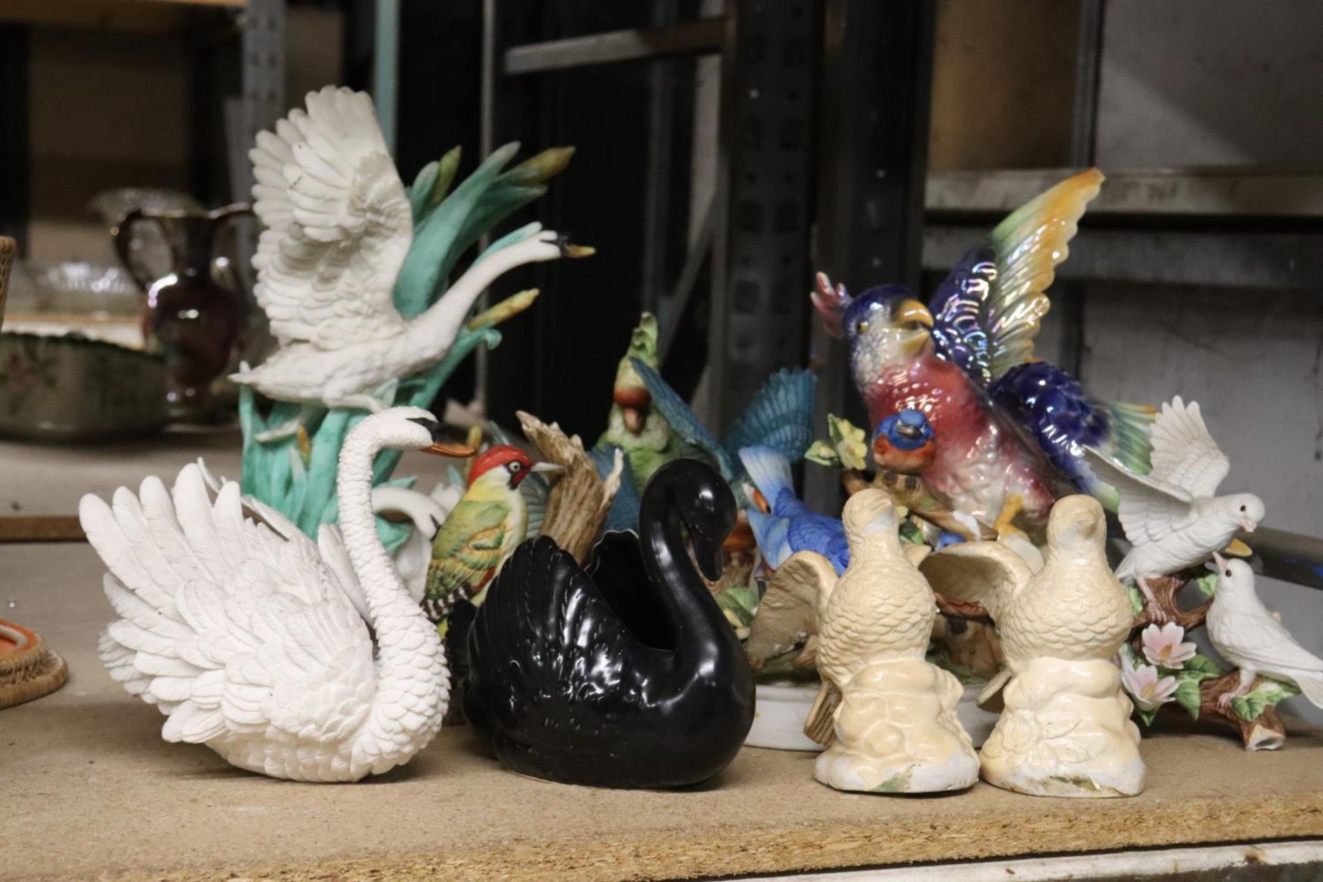 A COLLECTION OF BIRD FIGURINES TO INCLUDE SWANS, A PARROT, WOODPECKER, ETC