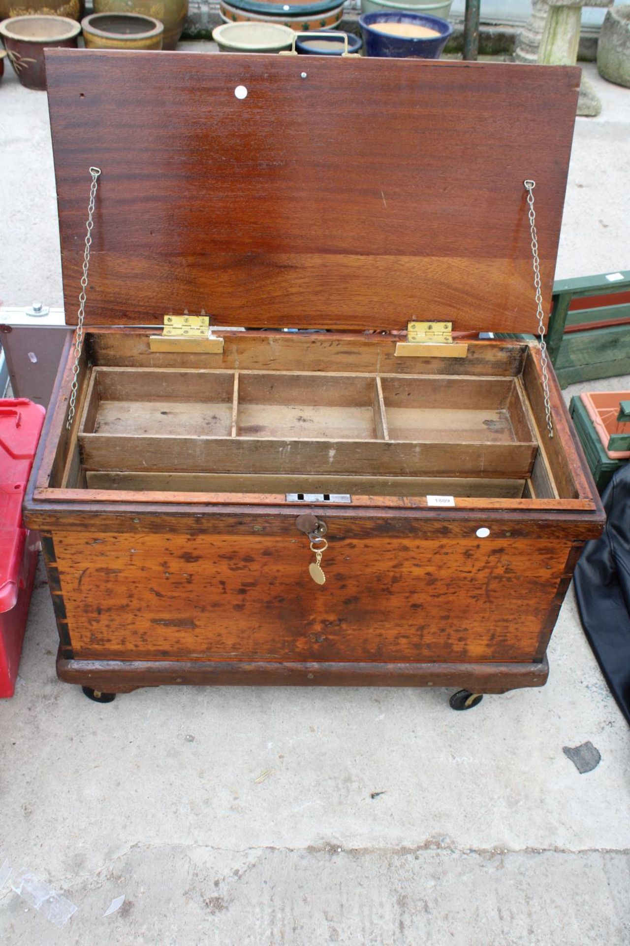 A VINTAGE WOODEN TOOL CHEST WITH FOUR WHEELS TO THE BASE