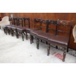 A SET OF 8 VICTORIAN OAK DINING CHAIRS WITH CARVED TOP RAIL ON TURNED AND FLUTED LEGS