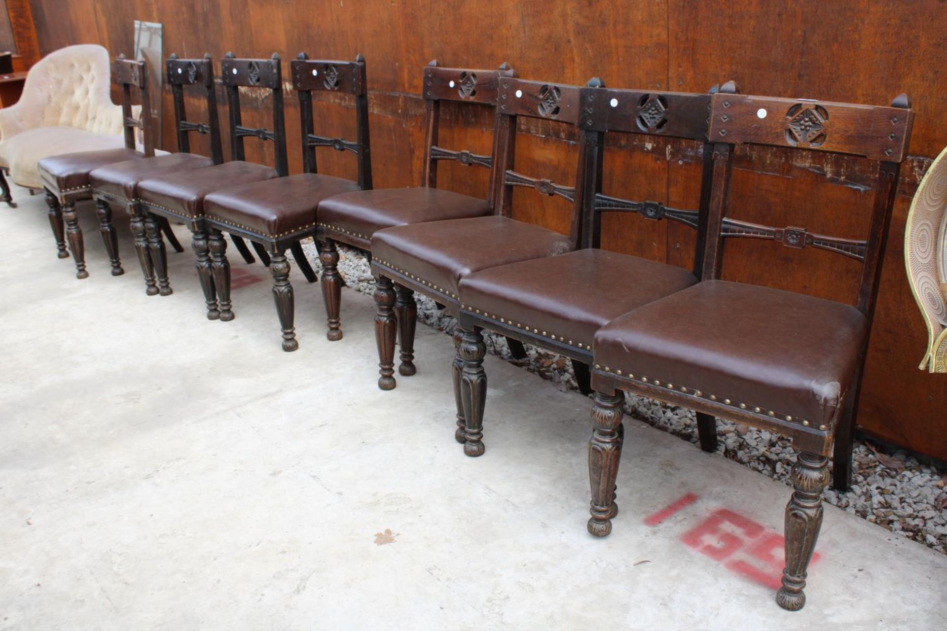 A SET OF 8 VICTORIAN OAK DINING CHAIRS WITH CARVED TOP RAIL ON TURNED AND FLUTED LEGS