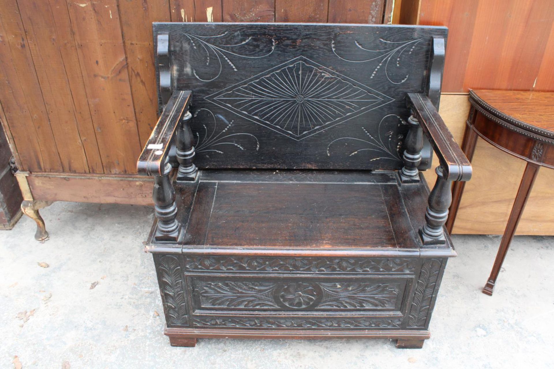 AN EARLY 20TH CENTURY OAK MONKS BENCH WITH CARVED PANELS