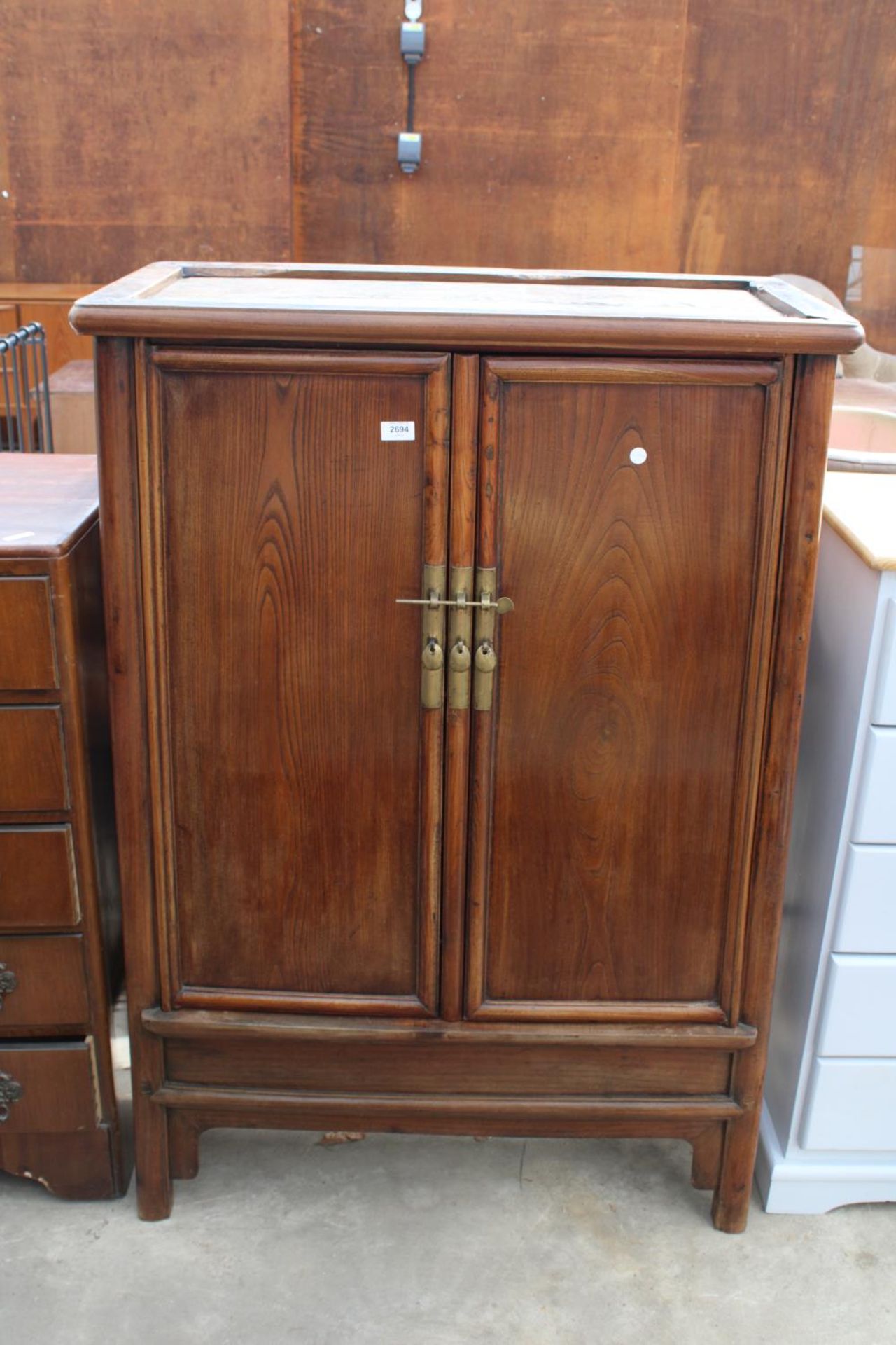 A CHINESE ELM TAPERING TWO DOOR CABINET WITH BRASS HANDLES AND LOCK WITH TWO INTERNAL DRAWERS, 36"